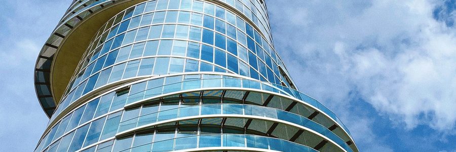 Tour de bureaux aux façades de verre courbes sous un ciel bleu